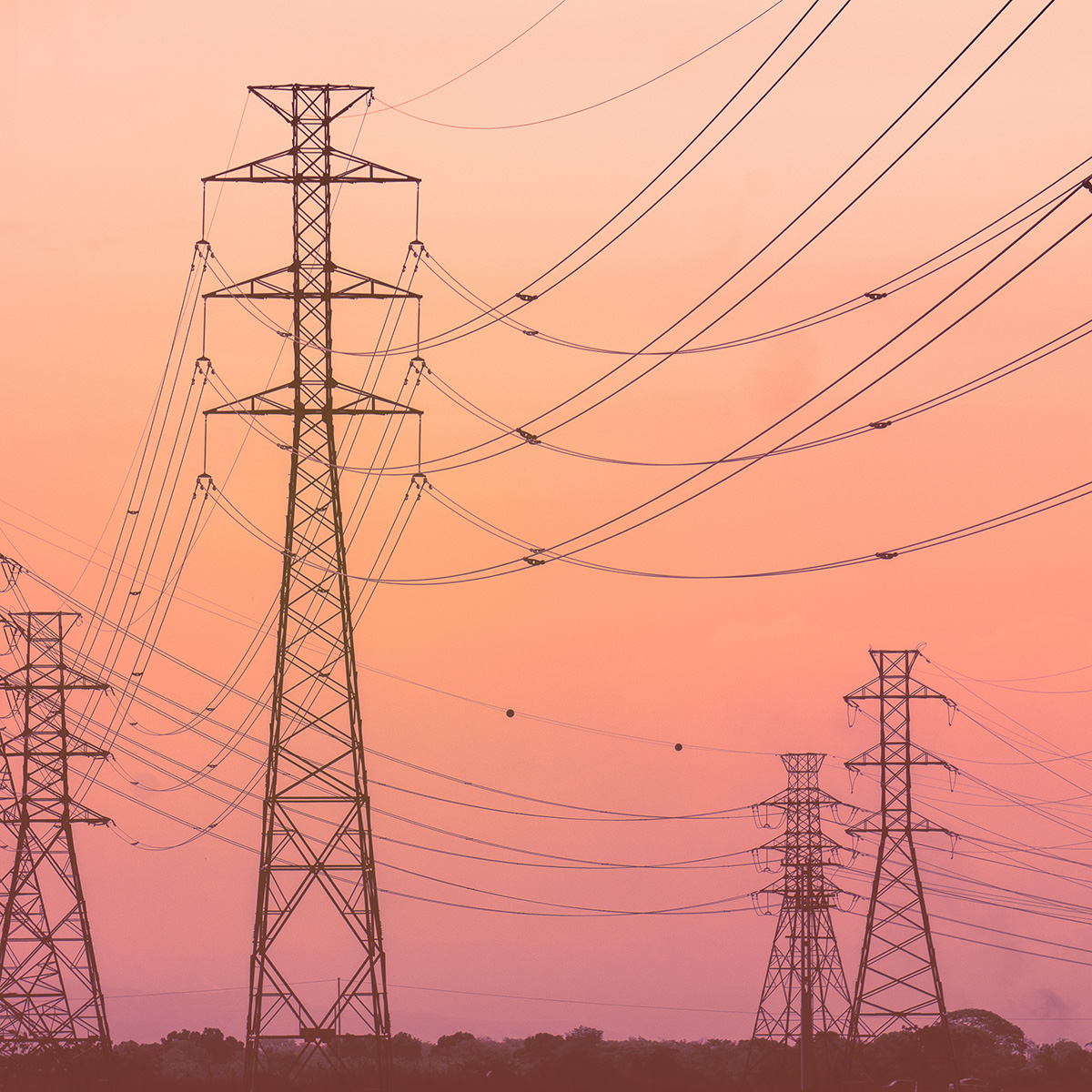Transmission towers and power lines under a fiery burnt orange sky