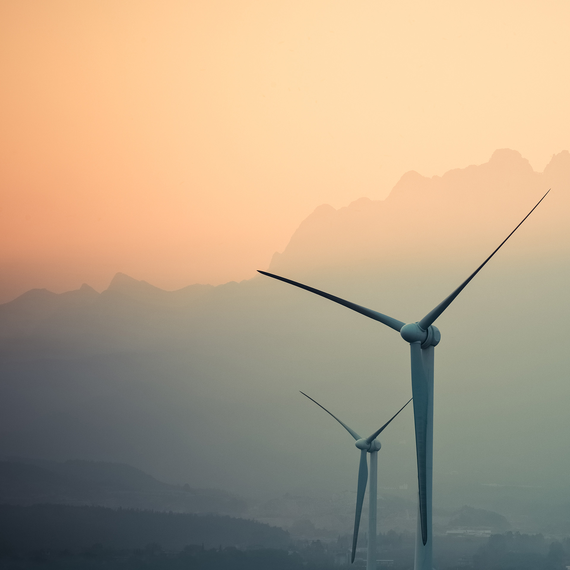 Wind turbines against a mountainous twilight sky